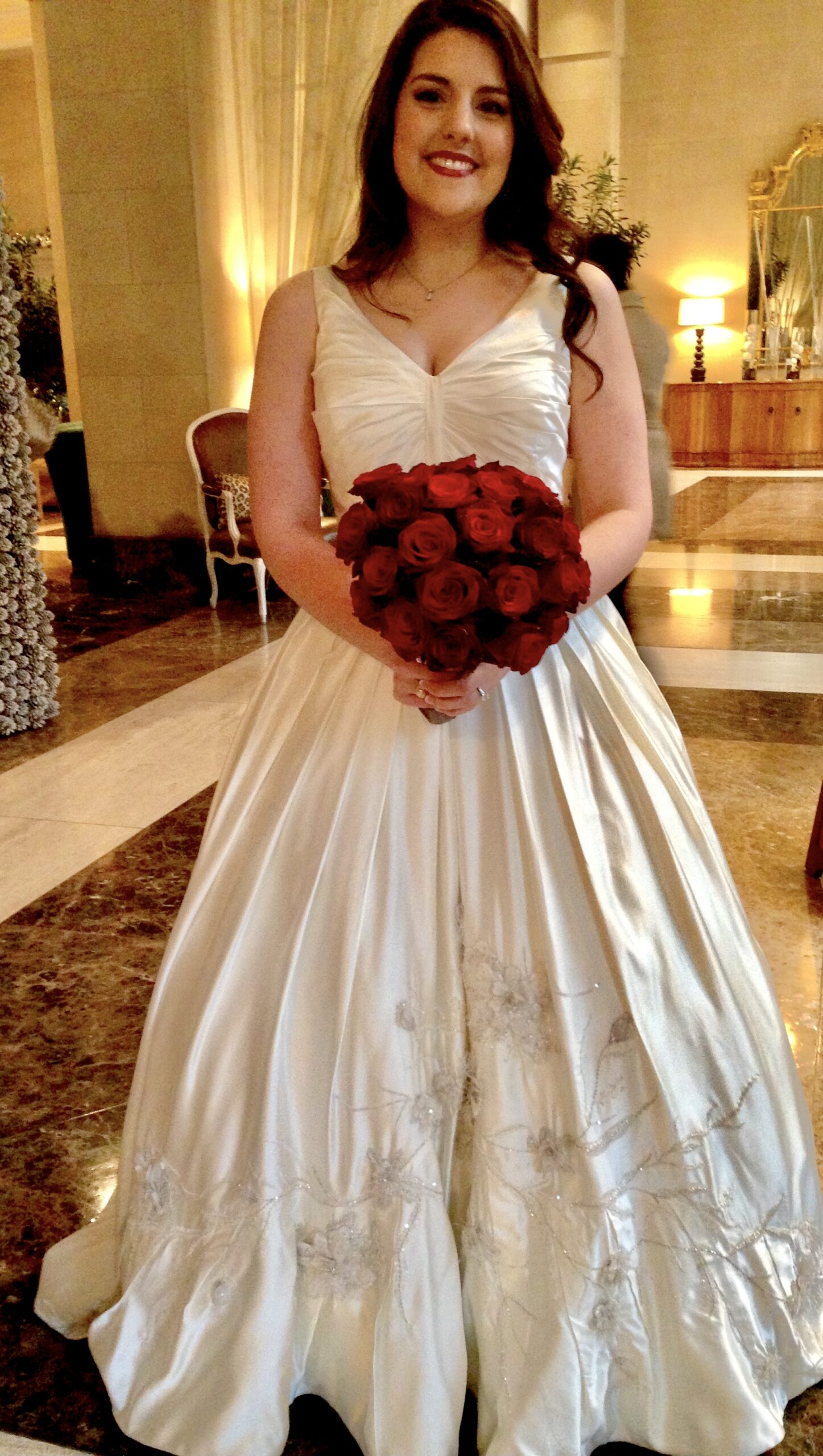A bride holding her bouquet of roses in the lobby.