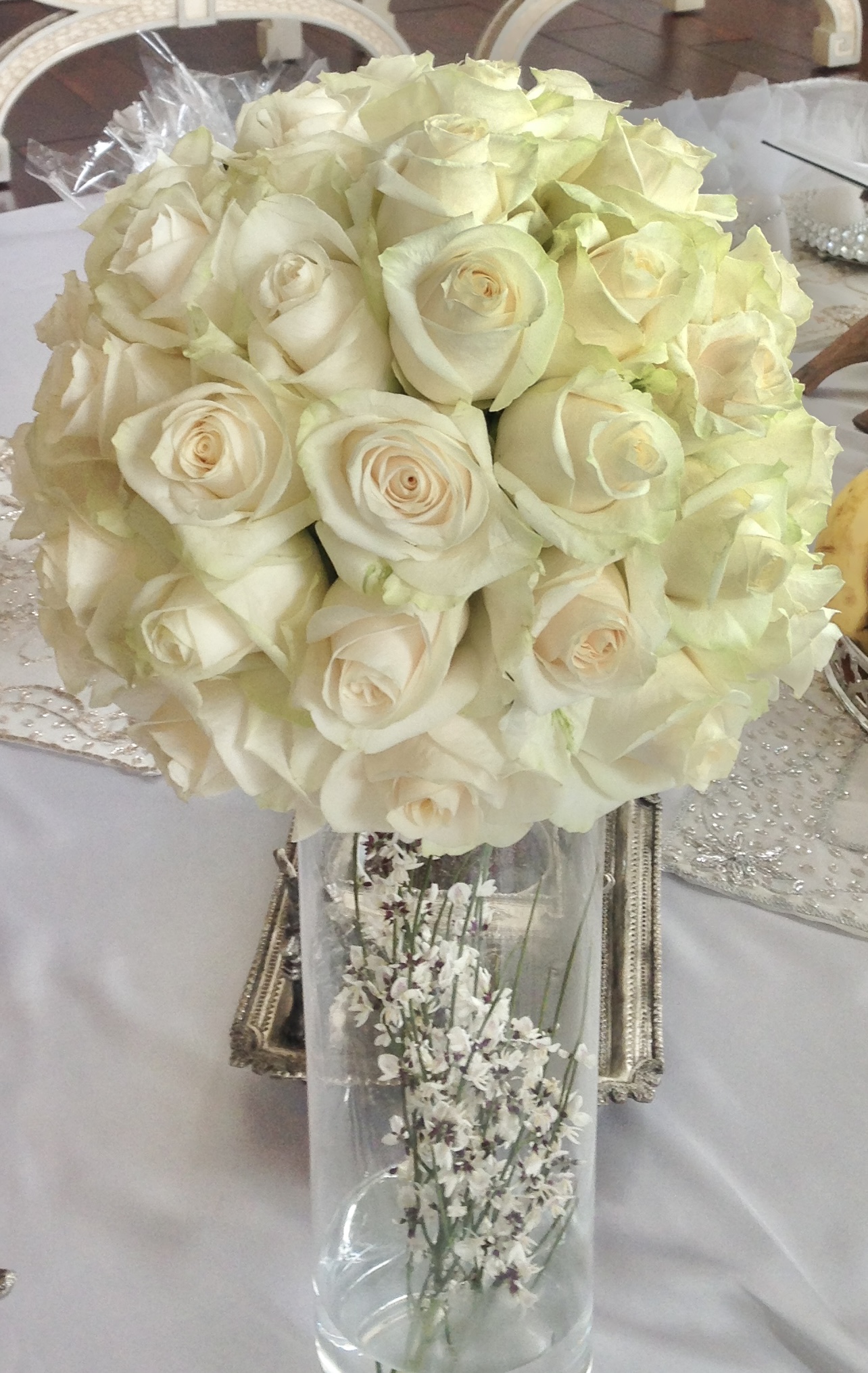 A vase filled with white roses on top of a table.