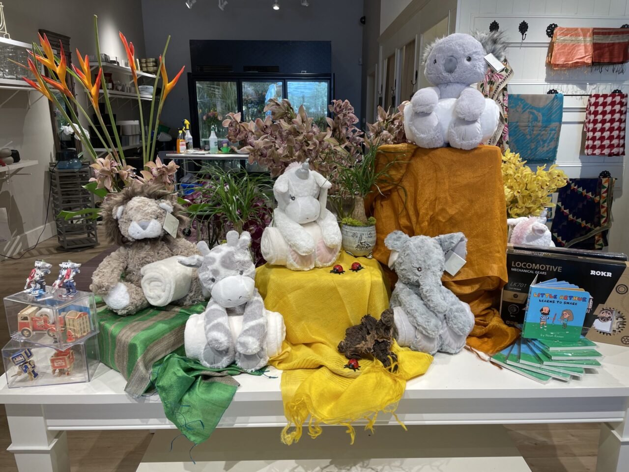 A display of stuffed animals and plants on a table.