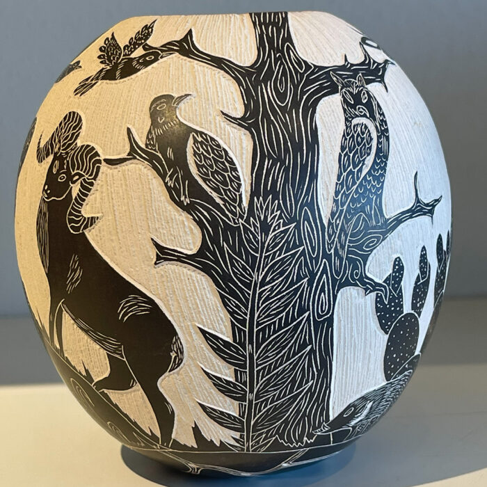 A black and white vase with trees and animals